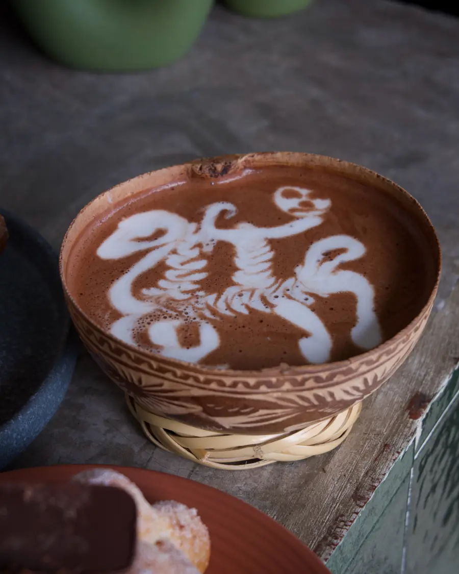 Chocolate caliente con arte de calavera en taza de barro