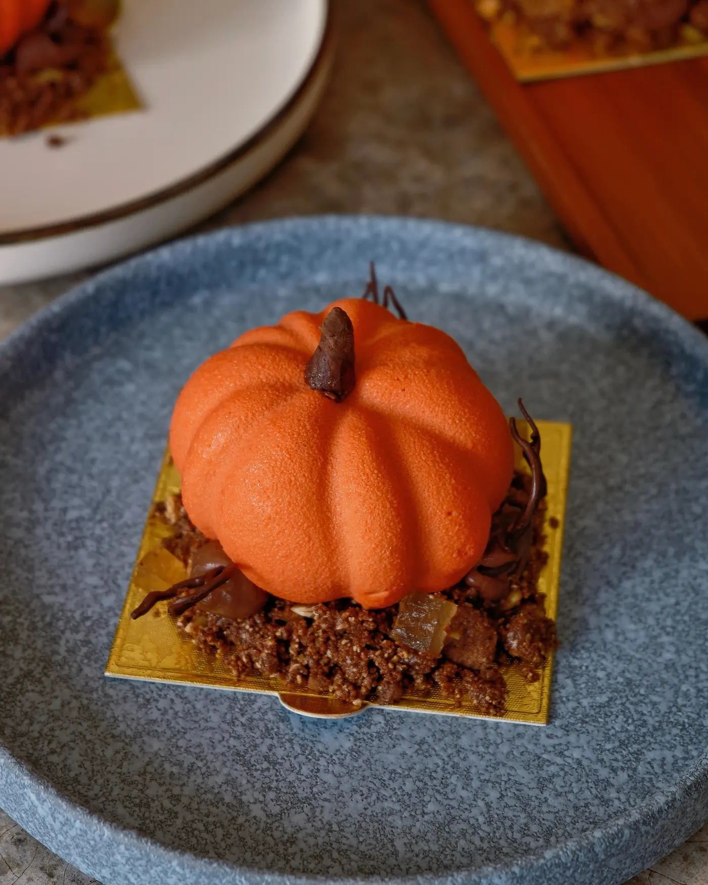 Postre en forma de calabaza naranja sobre strussel de chocolate y pepita