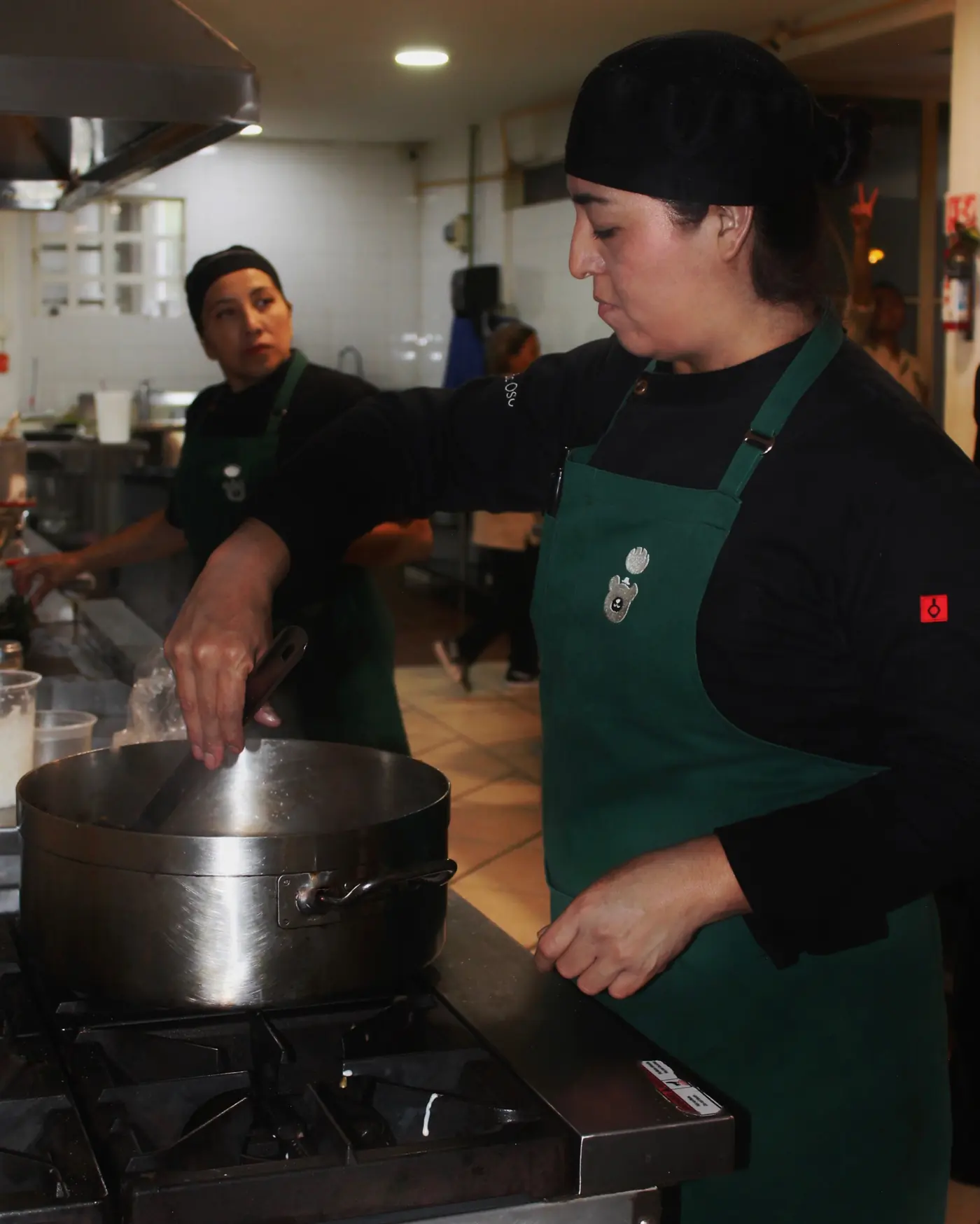 Cocineras preparando en la estufa con mandiles verdes