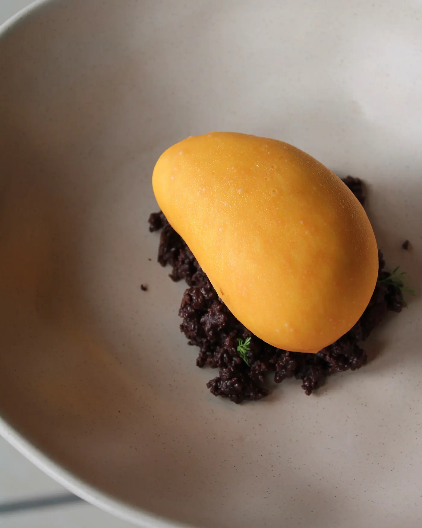 Postre con forma de mango sobre crumble de chocolate