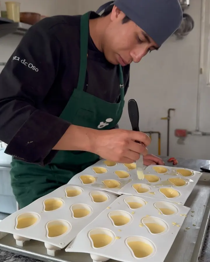 Repostero llenando moldes de postre con manga pastelera